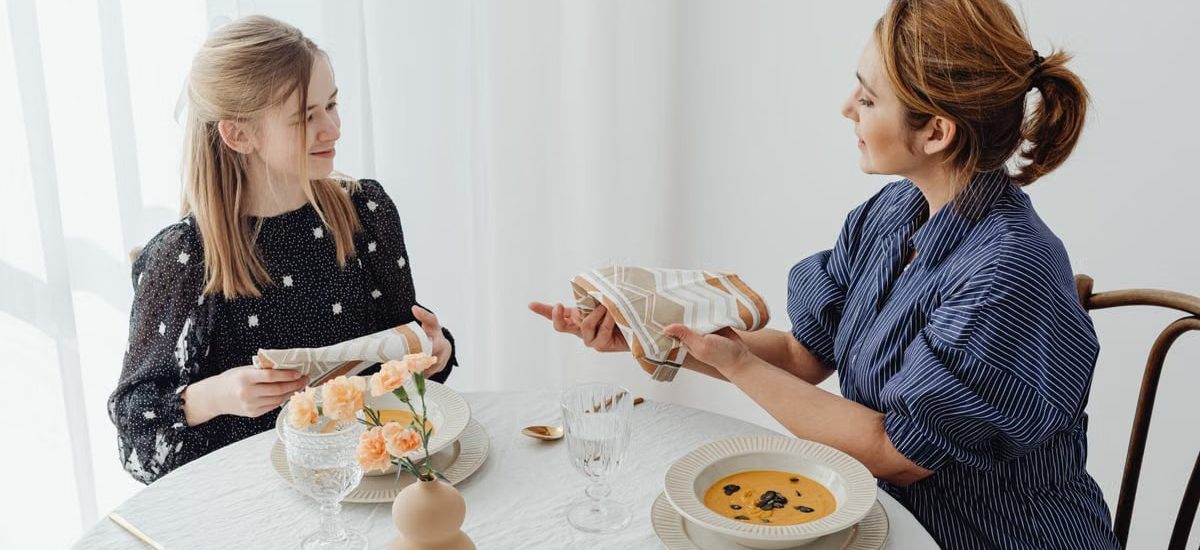 A mother and daughter share a meal, focusing on table etiquette and bonding over lunch.